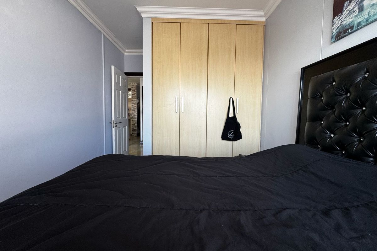 A bedroom featuring light wood-finish built-in wardrobes, decorative ceiling cornices, and a neutral wall palette.