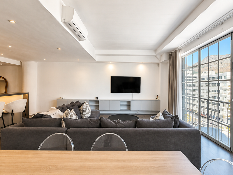 Modern open-plan living area featuring a sleek breakfast bar, built-in cabinetry, and expansive windows offering bright natural light and urban views.