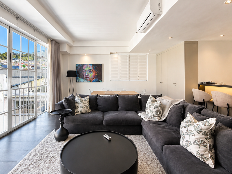 Modern open-plan living area featuring a breakfast bar, recessed lighting, split-system air conditioning, and large french doors leading to an outdoor space.