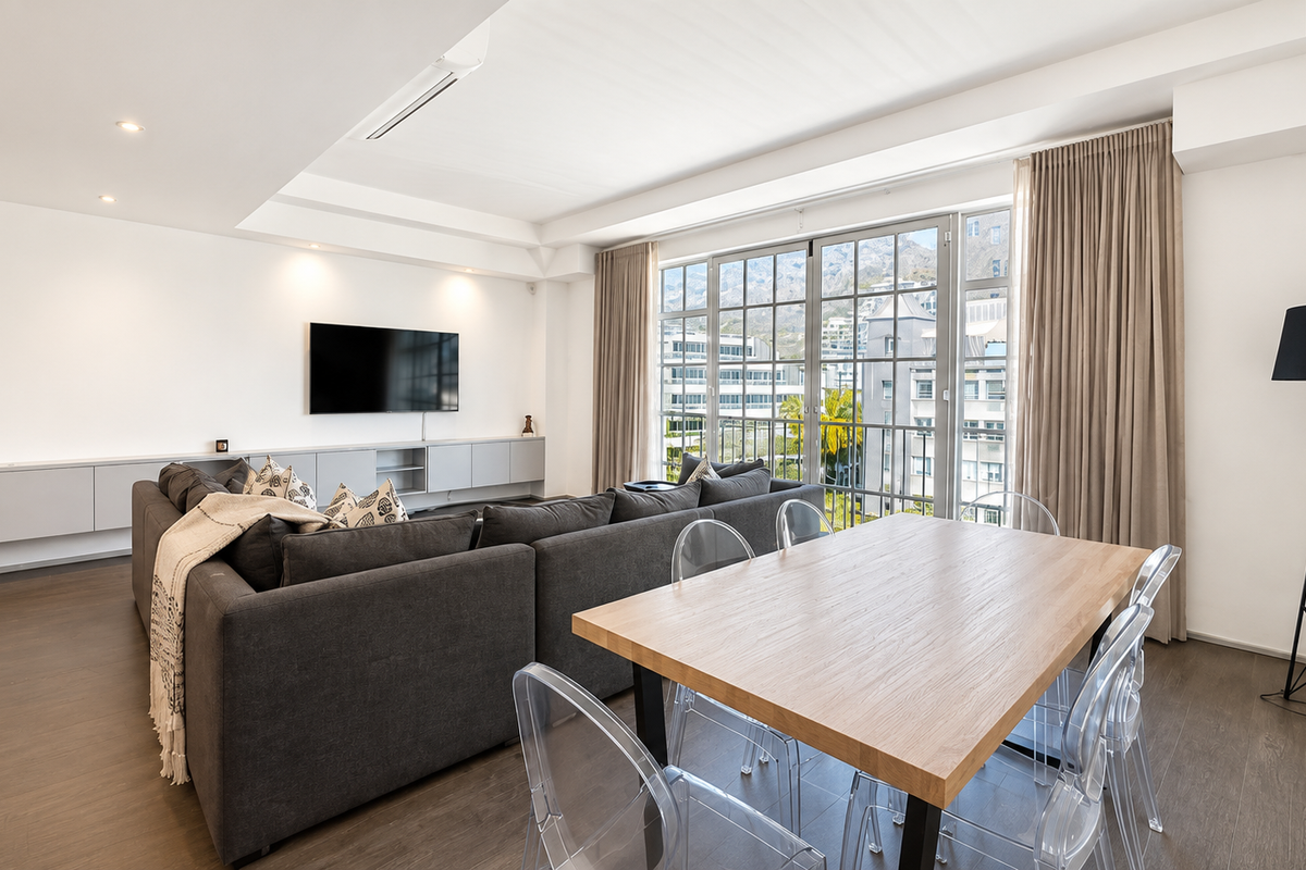 Spacious open-plan living and dining area featuring modern built-in cabinetry, recessed lighting, ducted air conditioning, and large glass doors with mountain views.