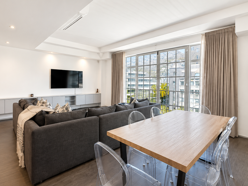 Spacious open-plan living and dining area featuring modern built-in cabinetry, recessed lighting, ducted air conditioning, and large glass doors with mountain views.