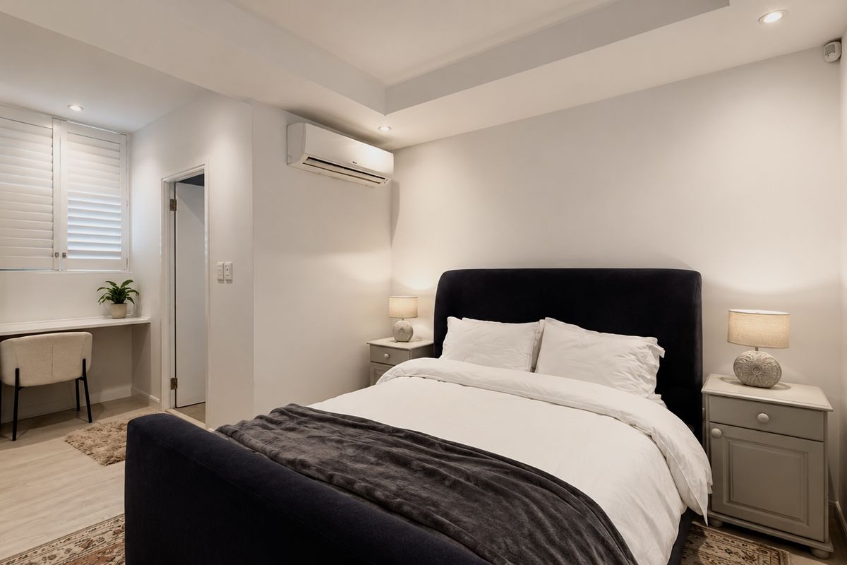 A well-maintained bedroom featuring a built-in desk, plantation shutters, split-system air conditioning, and recessed lighting.