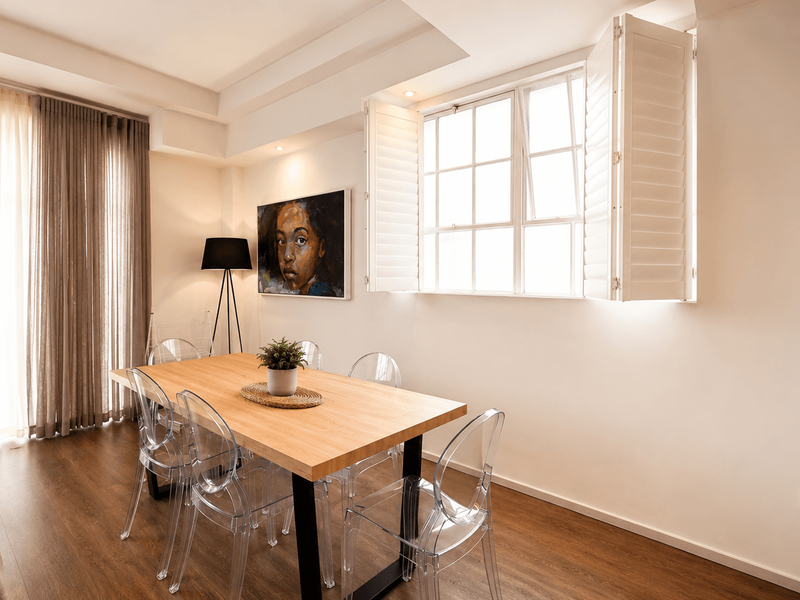 A bright and modern dining area featuring laminate flooring, recessed lighting, and plantation shutters, creating a warm and inviting atmosphere.