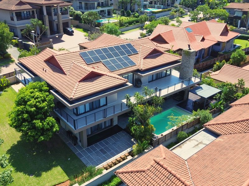 Aerial view of a modern residential property featuring a tiled roof with solar panels, a swimming pool, and a spacious balcony.