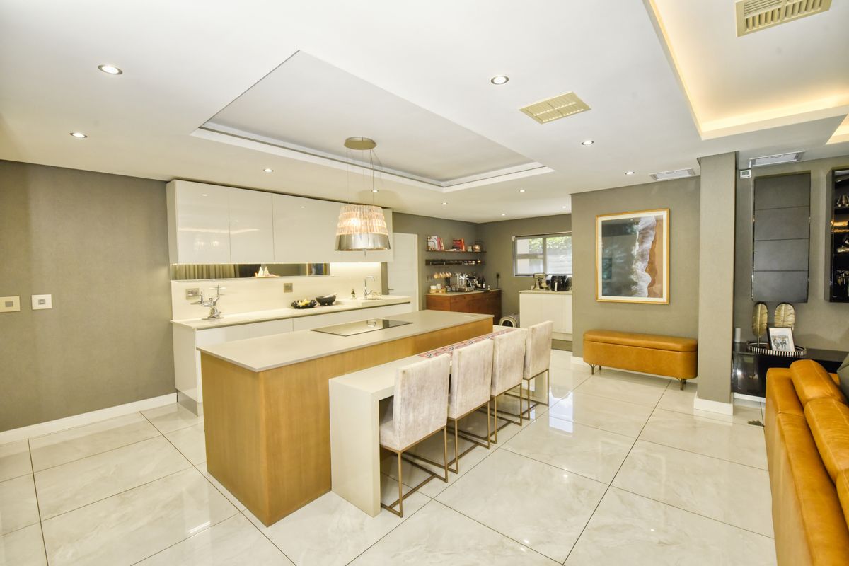Modern, well-appointed kitchen featuring a large central island with integrated hob, sleek cabinetry, recessed lighting, and polished tile flooring.