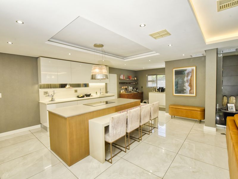 Modern, well-appointed kitchen featuring a large central island with integrated hob, sleek cabinetry, recessed lighting, and polished tile flooring.
