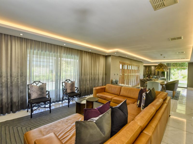 Spacious open-plan living and dining area featuring recessed ceiling lighting, large sliding glass doors, and polished tiled flooring.