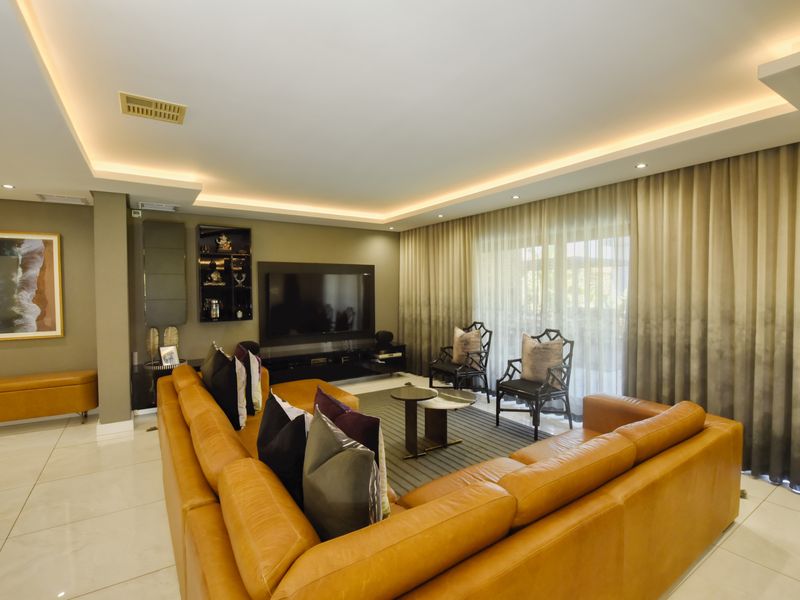 Spacious living room featuring modern recessed cove lighting, sleek tiled flooring, and large sliding glass doors leading to an outdoor area.
