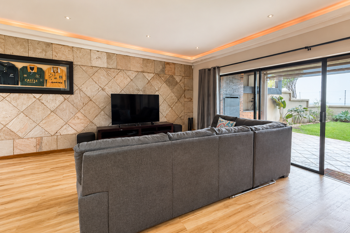 Spacious living room featuring a stone tile accent wall, recessed ceiling lighting, and large sliding glass doors providing seamless access to the outdoor patio area.