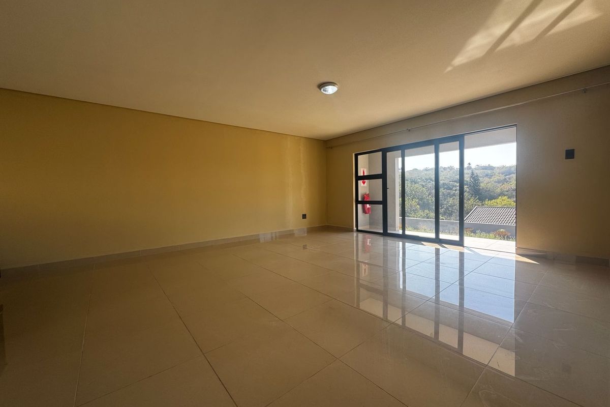 A spacious, empty living area featuring large sliding glass doors that provide natural light and access to an outdoor view.