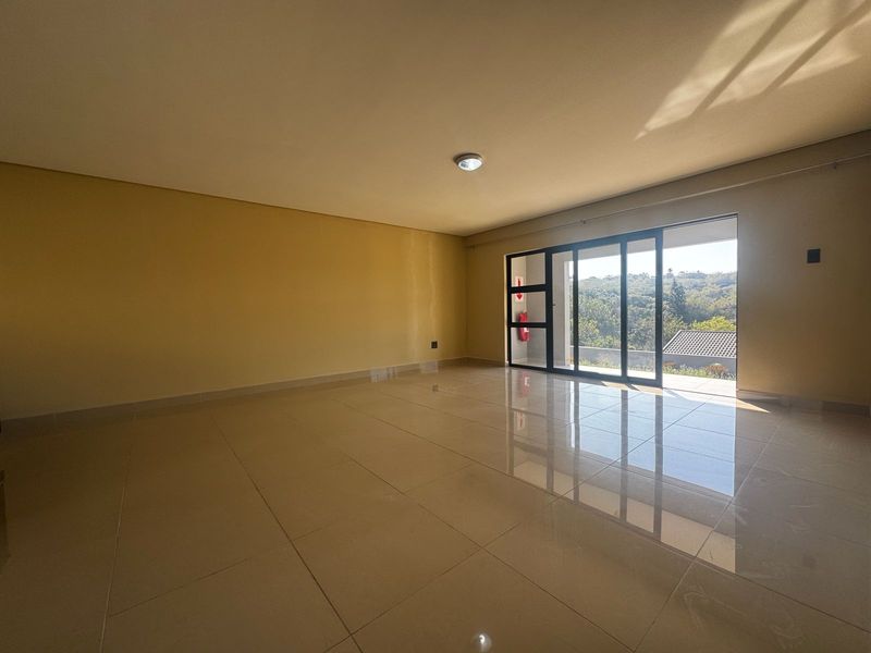 A spacious, empty living area featuring large sliding glass doors that provide natural light and access to an outdoor view.