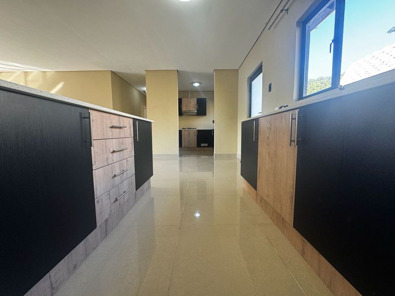 Modern kitchen featuring dual-tone cabinetry, stone countertops, and tiled flooring, offering a clean and functional workspace.