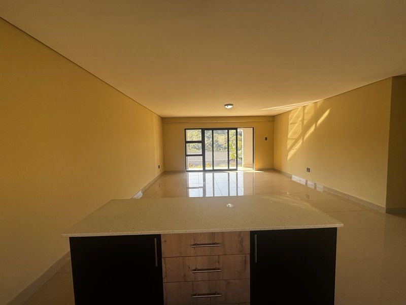 Spacious open-plan living area featuring a modern kitchen island with built-in cabinetry, tiled flooring, and large sliding glass doors leading to the exterior.