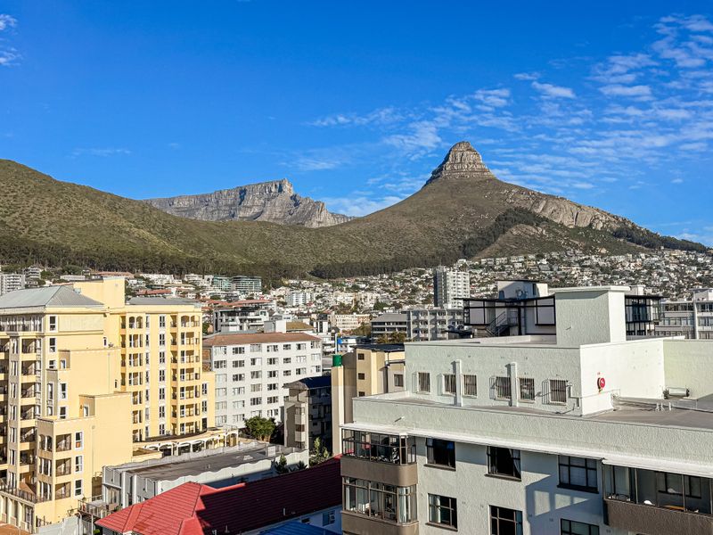 A clear, elevated urban view showcasing the surrounding cityscape with prominent mountain scenery in the background.
