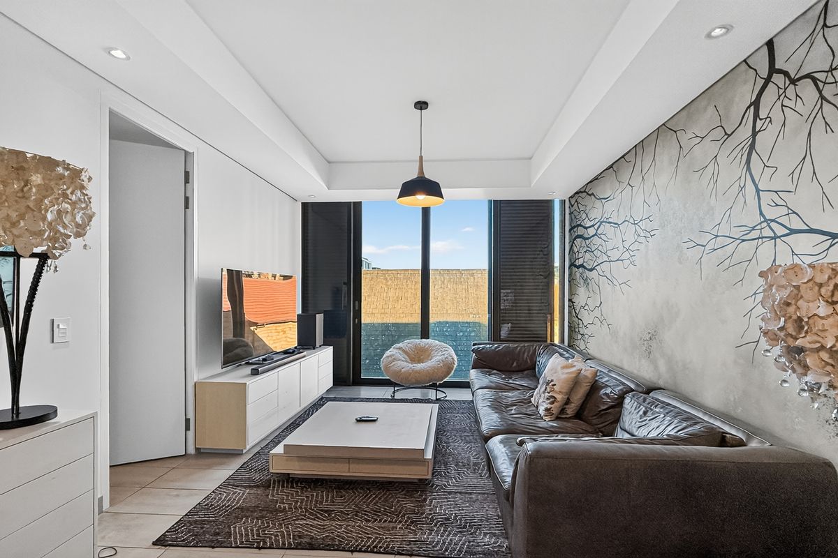 Modern living room featuring recessed ceiling lighting, tiled floors, and large sliding glass doors leading to an outdoor area.