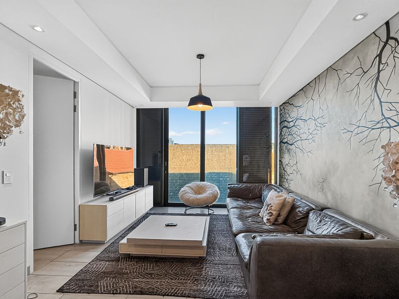 Modern living room featuring recessed ceiling lighting, tiled floors, and large sliding glass doors leading to an outdoor area.