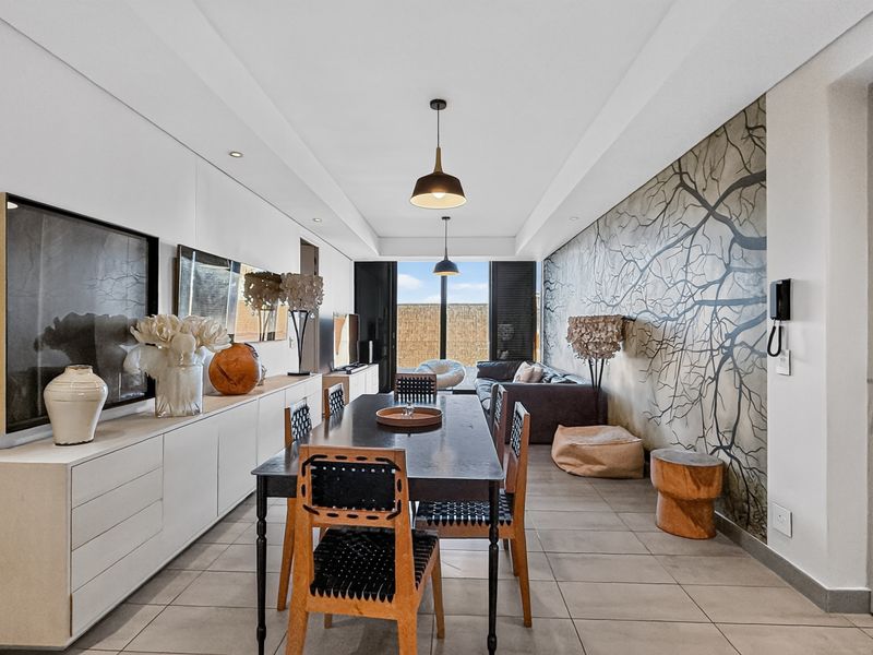 Spacious open-plan living and dining area featuring tiled floors, recessed lighting, built-in cabinetry, and large sliding doors leading to an outdoor space.