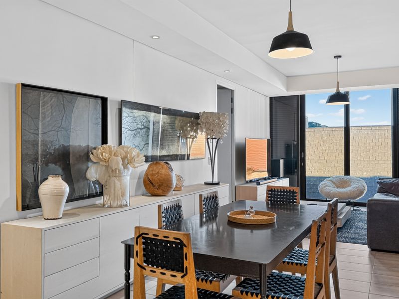 Modern open-plan living and dining area featuring tiled flooring, recessed downlights, and large sliding glass doors leading to an outdoor space.