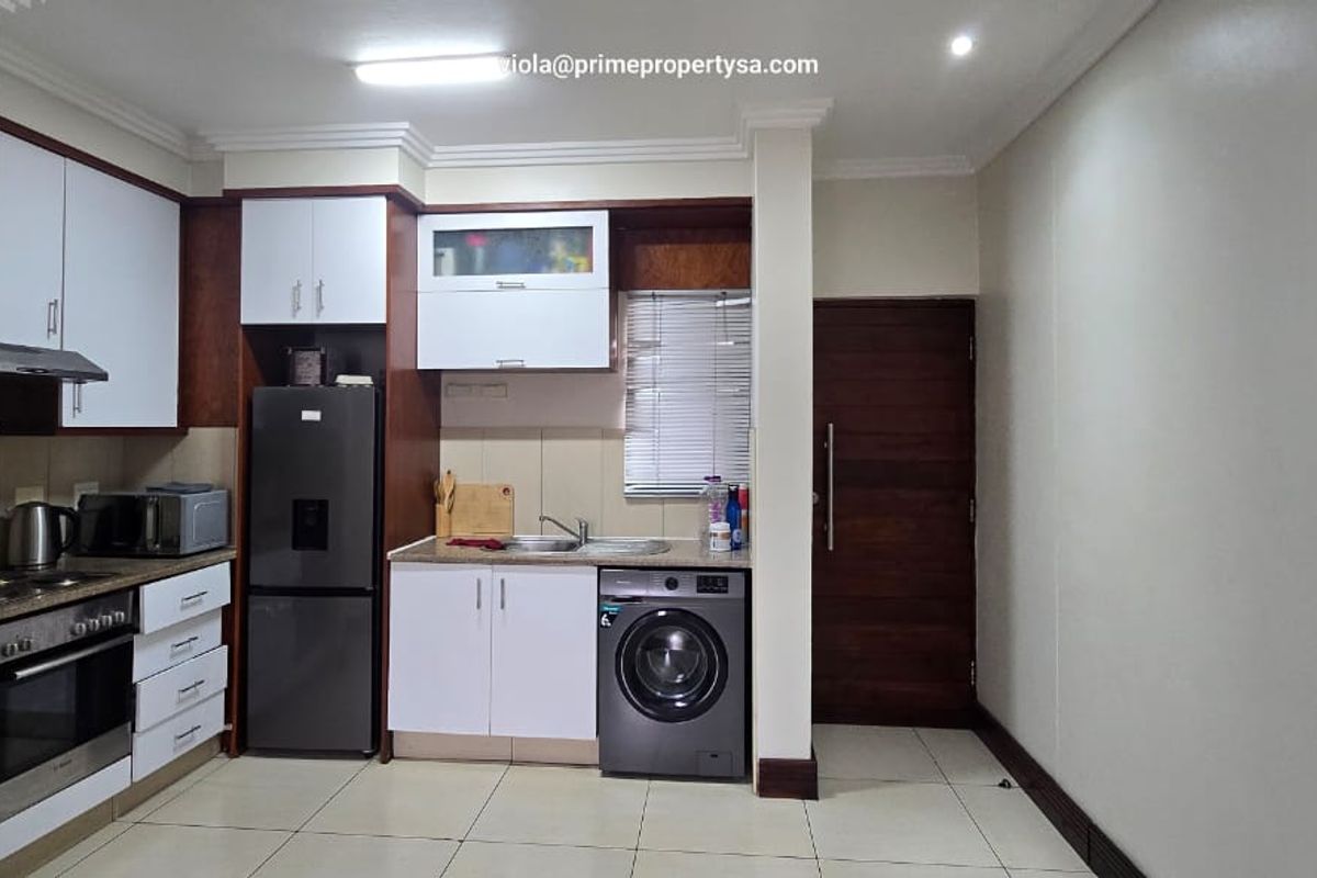 A functional kitchen featuring built-in cabinetry, a stainless steel sink, integrated oven and hob, and tiled flooring with a clean, modern layout.