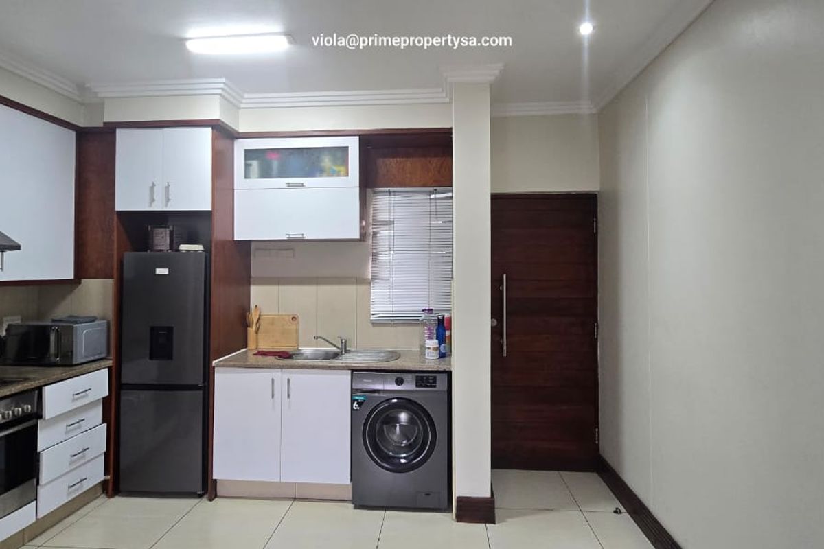 A functional kitchen featuring built-in cabinetry, stainless steel sink, integrated oven, and tiled flooring, providing a practical and efficient cooking and laundry space.