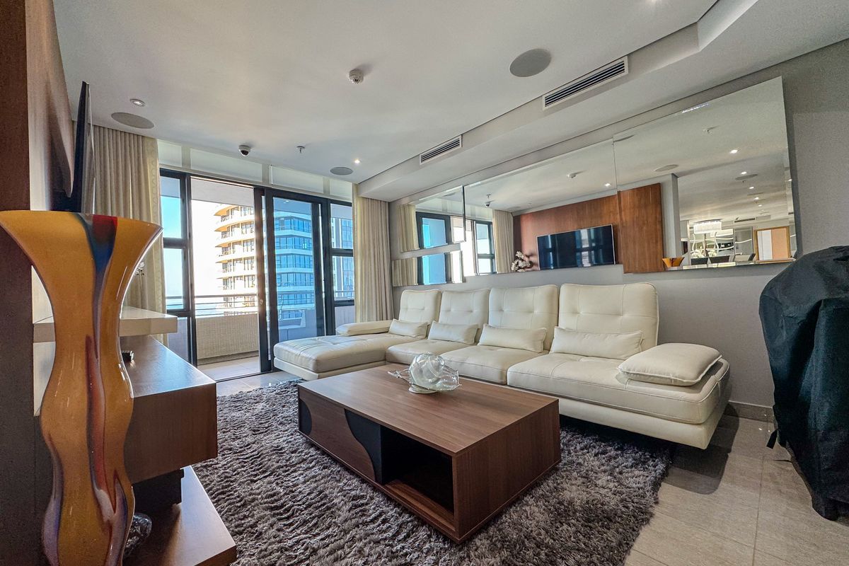 Modern living room featuring tiled floors, ducted air conditioning, recessed lighting, and large sliding doors leading to a private balcony.