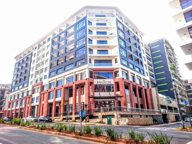 A modern multi-story apartment building featuring a striking brick and glass facade with prominent balconies and contemporary architectural design.