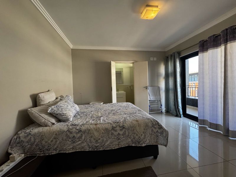 Spacious bedroom featuring tiled flooring, direct access to a private balcony, and an en-suite bathroom.