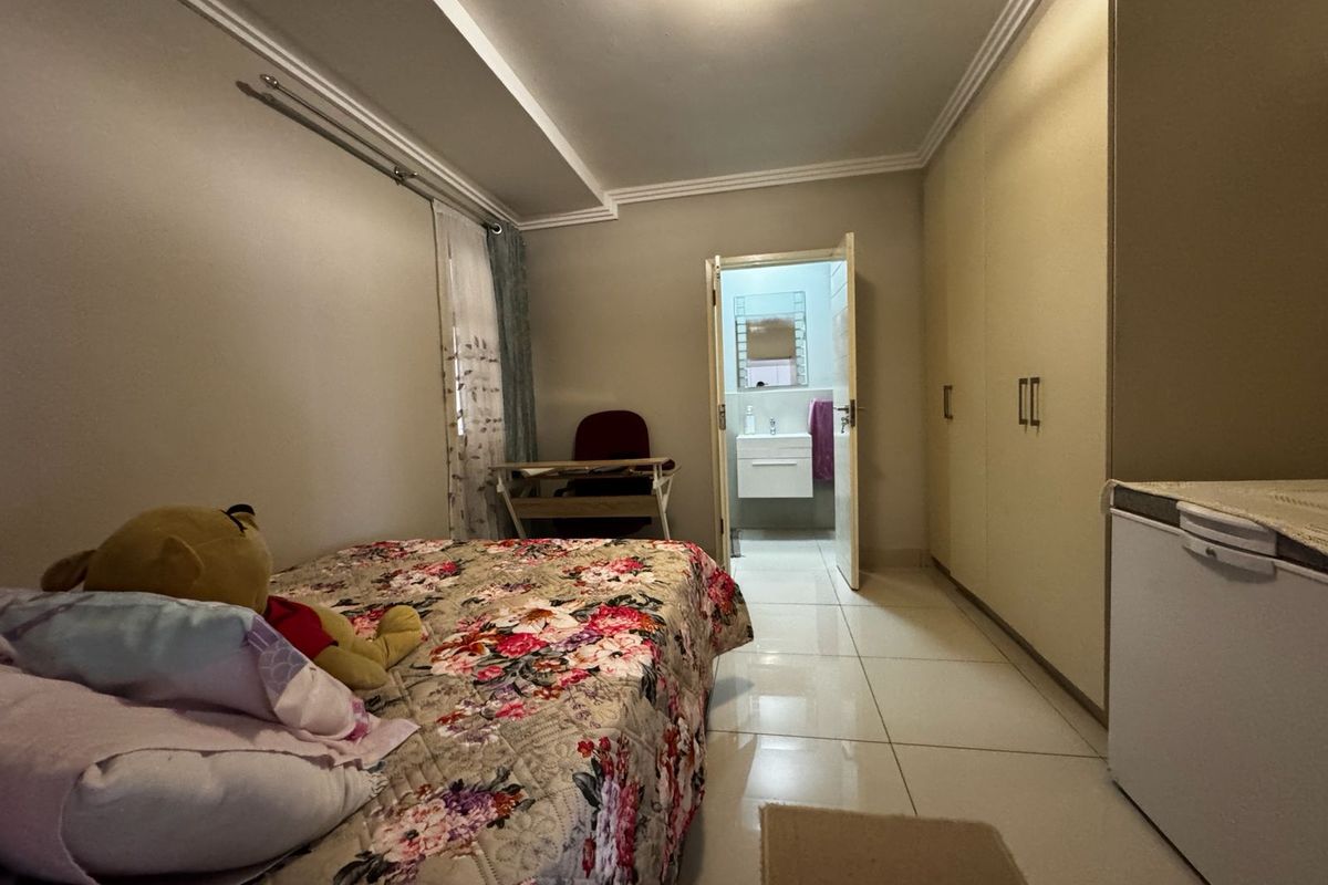 Bedroom featuring built-in cupboards, tiled flooring, and direct access to an en-suite bathroom.