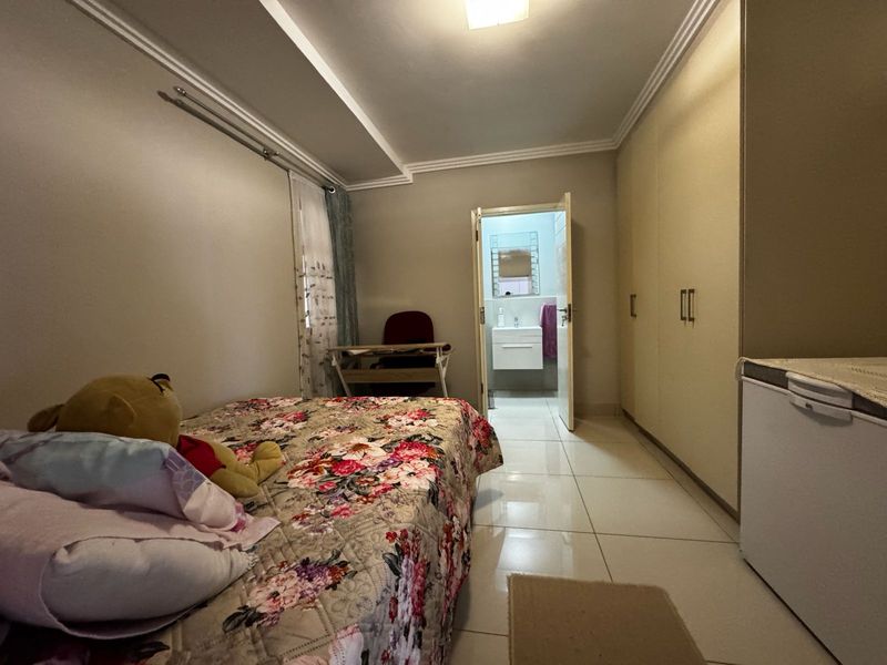 Bedroom featuring built-in cupboards, tiled flooring, and direct access to an en-suite bathroom.