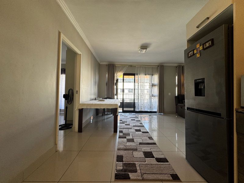 Open plan living area featuring tiled flooring and a sliding glass door leading to a balcony, providing natural light and access to outdoor space.