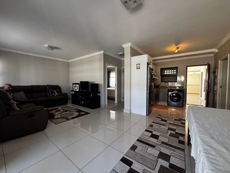 Spacious open-plan living area featuring polished floor tiles, integrated kitchen cabinetry, and a seamless flow between the lounge and kitchen space.