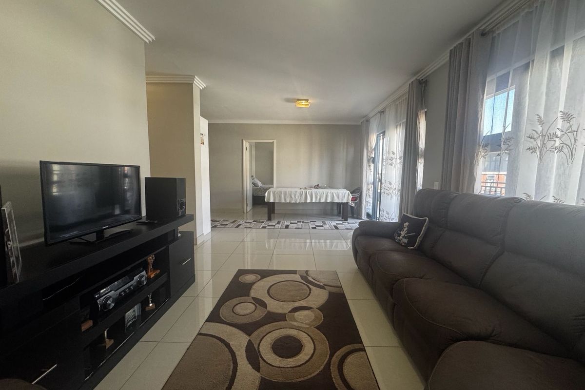 Spacious living room featuring polished tile flooring, crown molding, and large sliding glass doors that provide ample natural light.