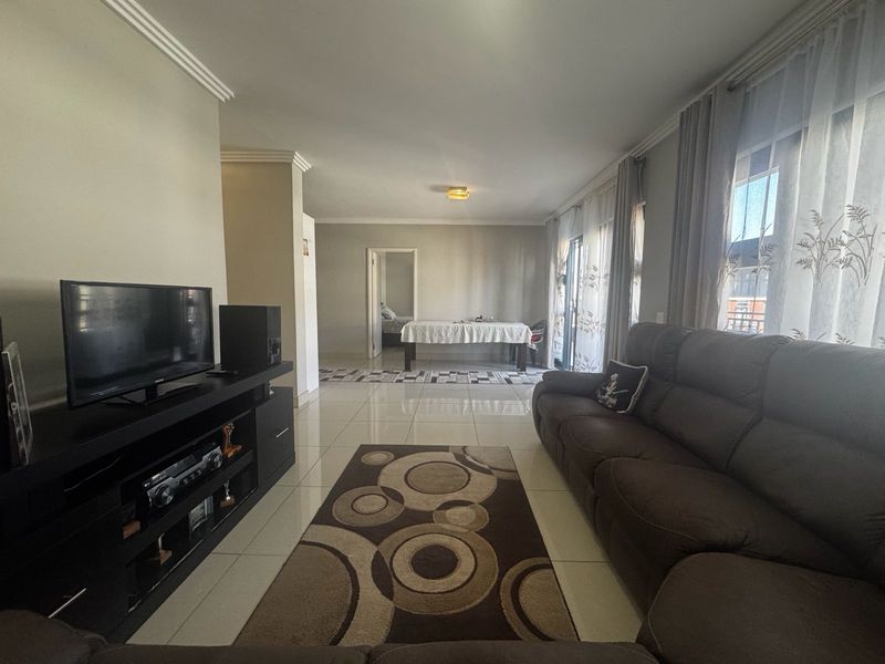 Spacious living room featuring polished tile flooring, crown molding, and large sliding glass doors that provide ample natural light.