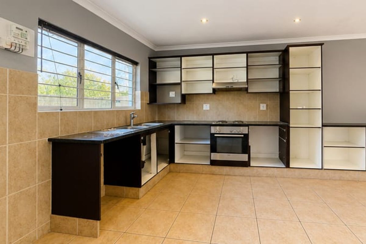 A functional kitchen space featuring built-in cabinetry, a built-in oven with hob, and tiled finishes, currently awaiting cabinet door replacements.