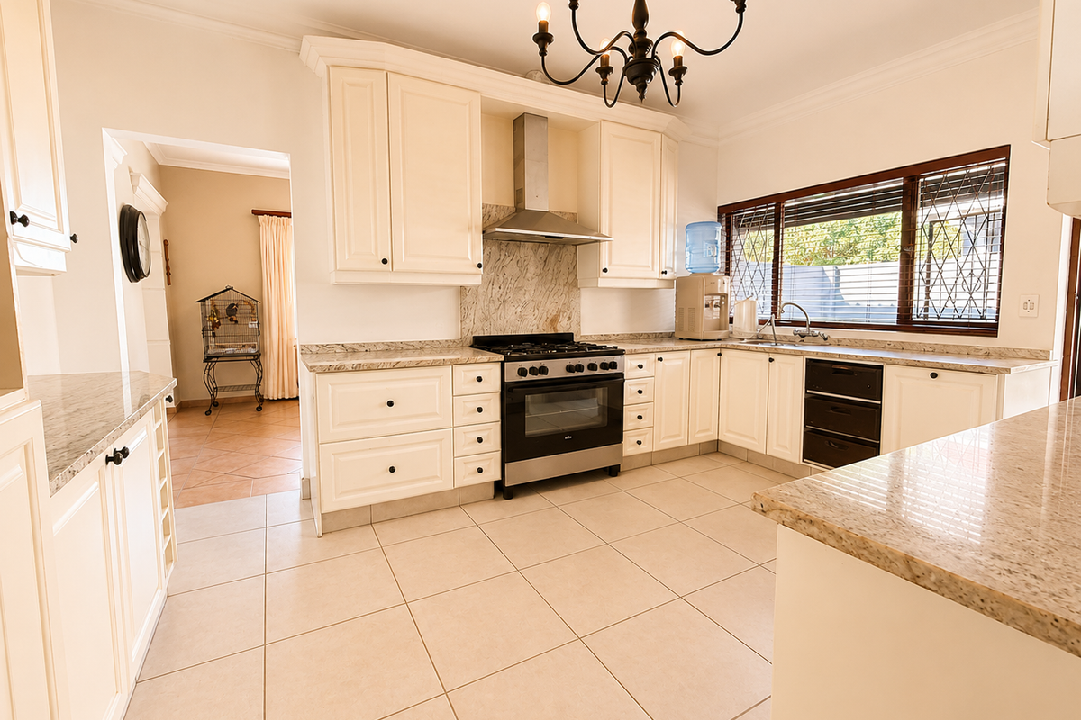 A spacious, well-maintained kitchen featuring granite countertops, ample cabinetry, a stainless steel gas hob, and an integrated oven with an extractor fan.