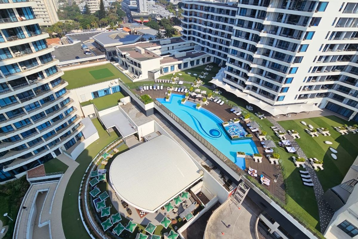 Aerial view of the penthouse complex featuring a large swimming pool, landscaped garden areas, and modern multi-story residential architecture.