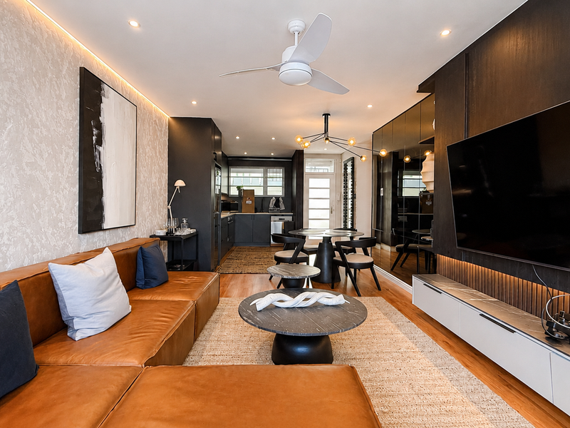 Modern open-plan living and kitchen area featuring high-end finishes, timber flooring, integrated cabinetry, and sophisticated recessed lighting throughout the space.