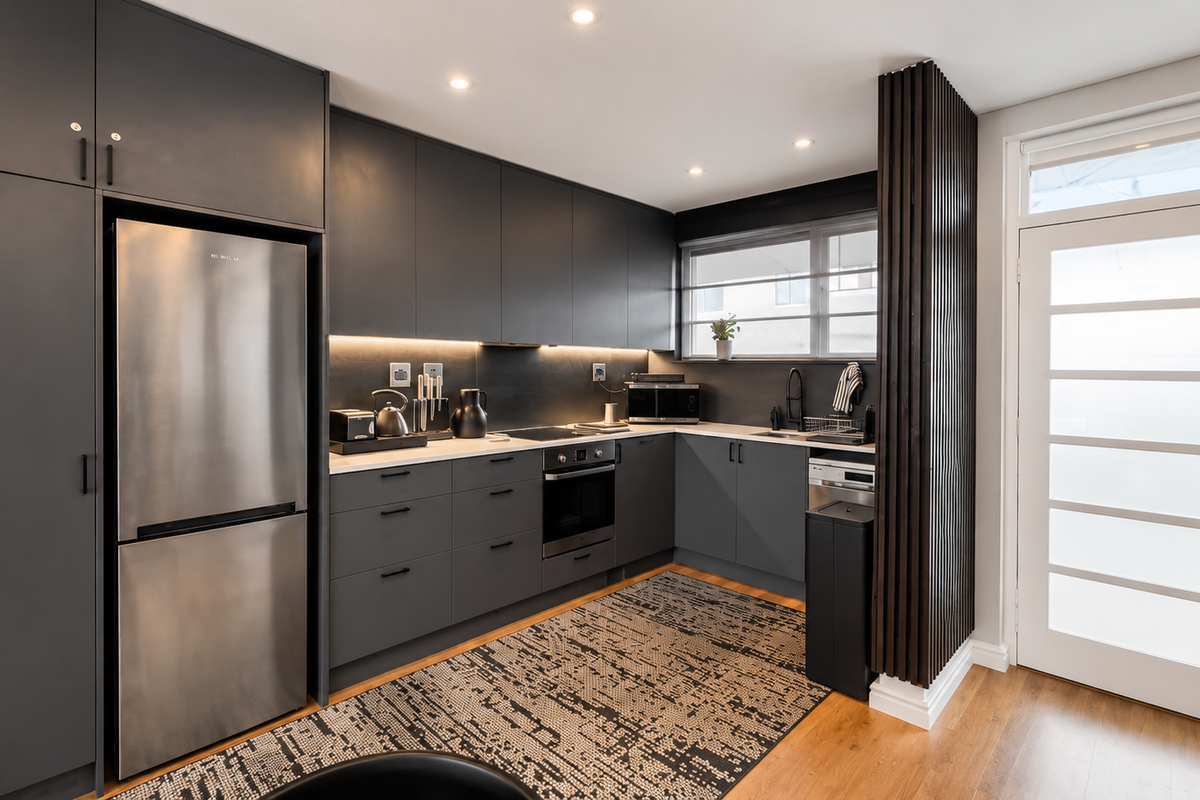 Modern kitchen featuring sleek dark cabinetry, integrated appliances, timber flooring, and a stylish slatted wood feature wall with direct exterior access.