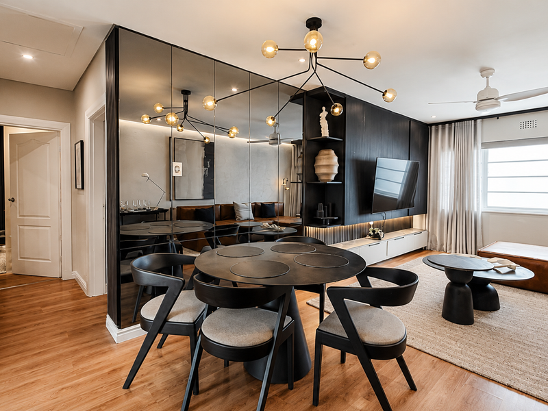 Modern open-plan living and dining area featuring sleek mirrored wall accents, built-in media cabinetry, recessed lighting, and warm laminate flooring throughout.