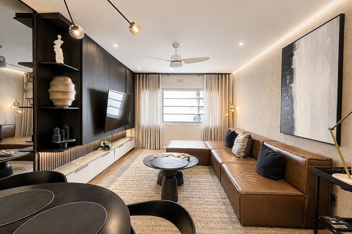 Modern, well-appointed living room featuring custom built-in cabinetry, integrated LED lighting, a ceiling fan, and a sophisticated mirrored feature wall.