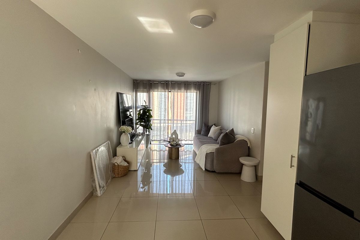 Open plan living area featuring polished tile flooring, neutral wall tones, and a sliding glass door providing access to the balcony.