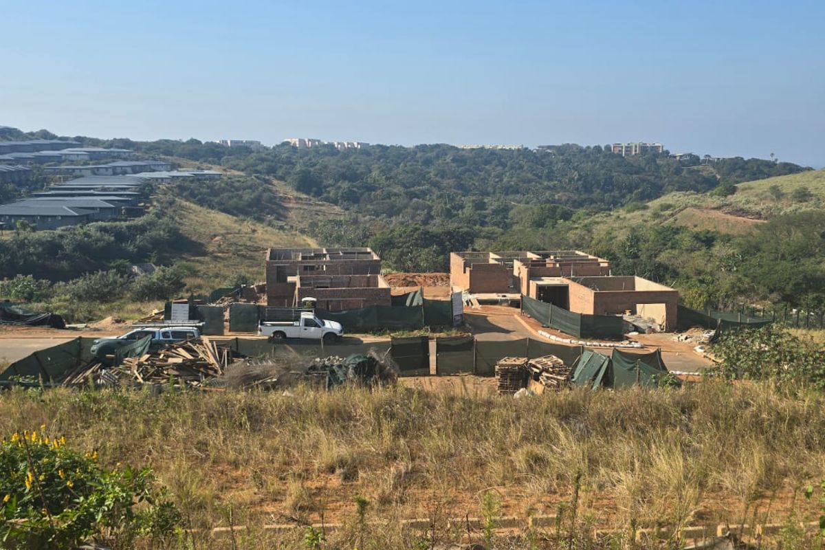 An elevated view of a residential development site featuring multiple brick structures under construction within a landscaped estate setting.