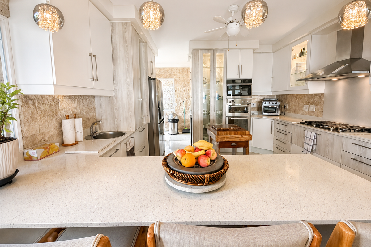 Modern kitchen featuring stone benchtops, integrated stainless steel appliances, gas cooktop, and stylish pendant lighting with a neutral color palette.