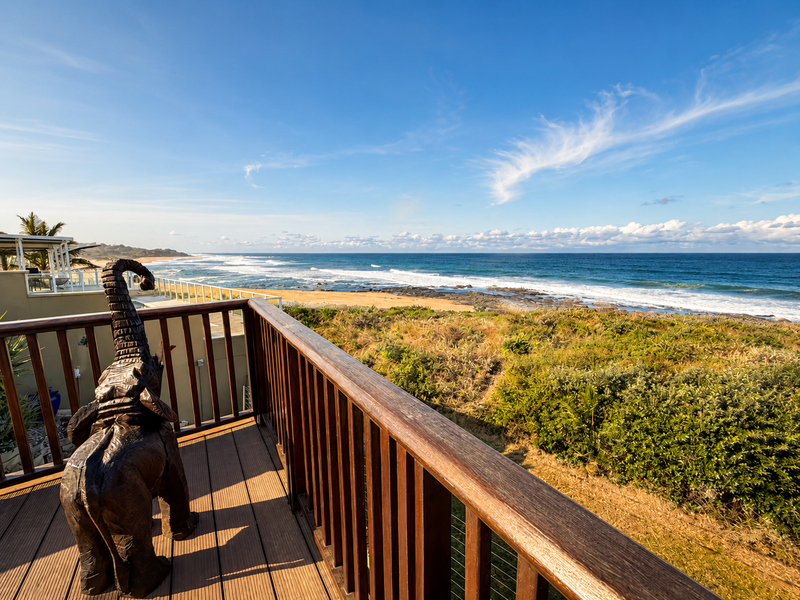 A spacious timber balcony offering expansive, elevated views of the coastline and ocean.