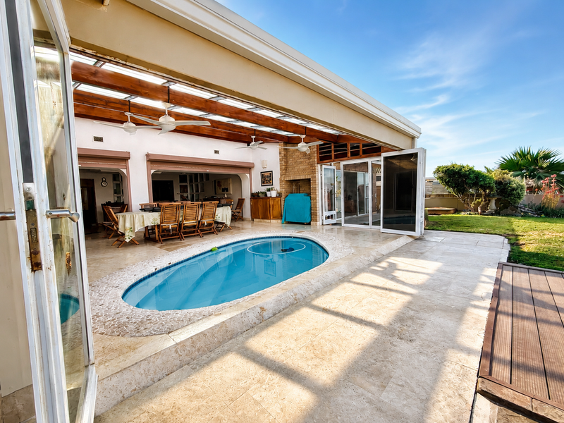 Spacious covered patio area featuring a built-in swimming pool, timber pergola, and seamless indoor-outdoor flow through large bi-fold doors.
