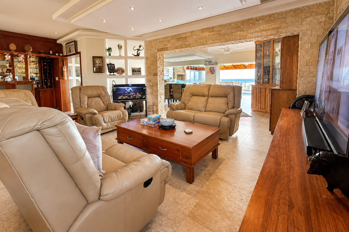 Spacious living room featuring a stone accent wall, built-in display shelving, recessed ceiling lighting, and tiled flooring, with an open flow to the patio area.