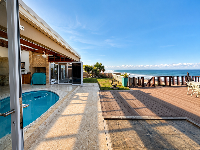 Spacious outdoor entertainment area featuring a swimming pool, timber decking, and a built-in fireplace, offering stunning ocean views.