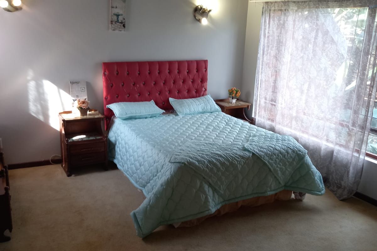 Spacious bedroom featuring a vaulted timber ceiling, wall-mounted air conditioning, and large windows allowing natural light.