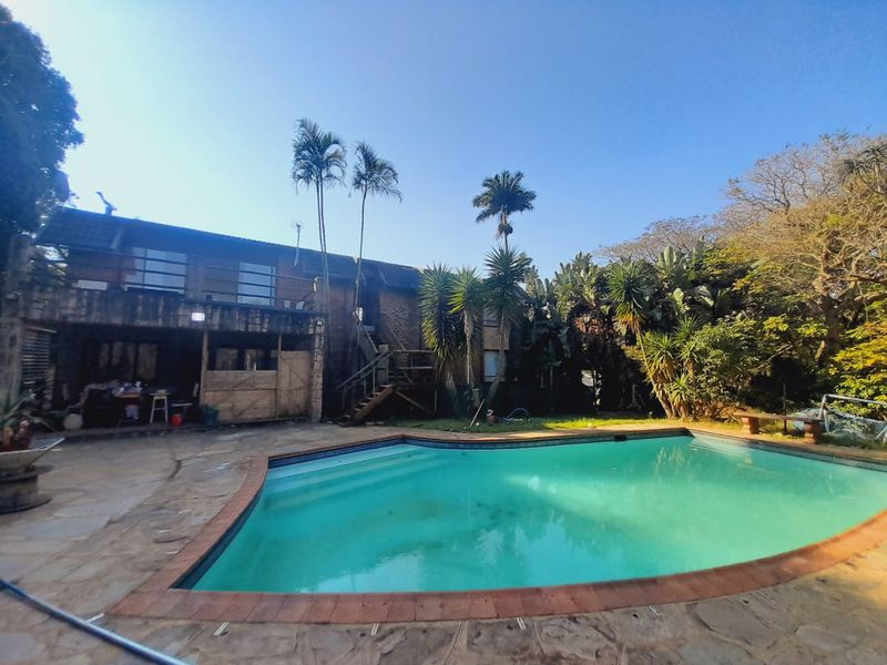 Outdoor pool area featuring a swimming pool, stone paved surround, and access to the rear building elevation with an external staircase.