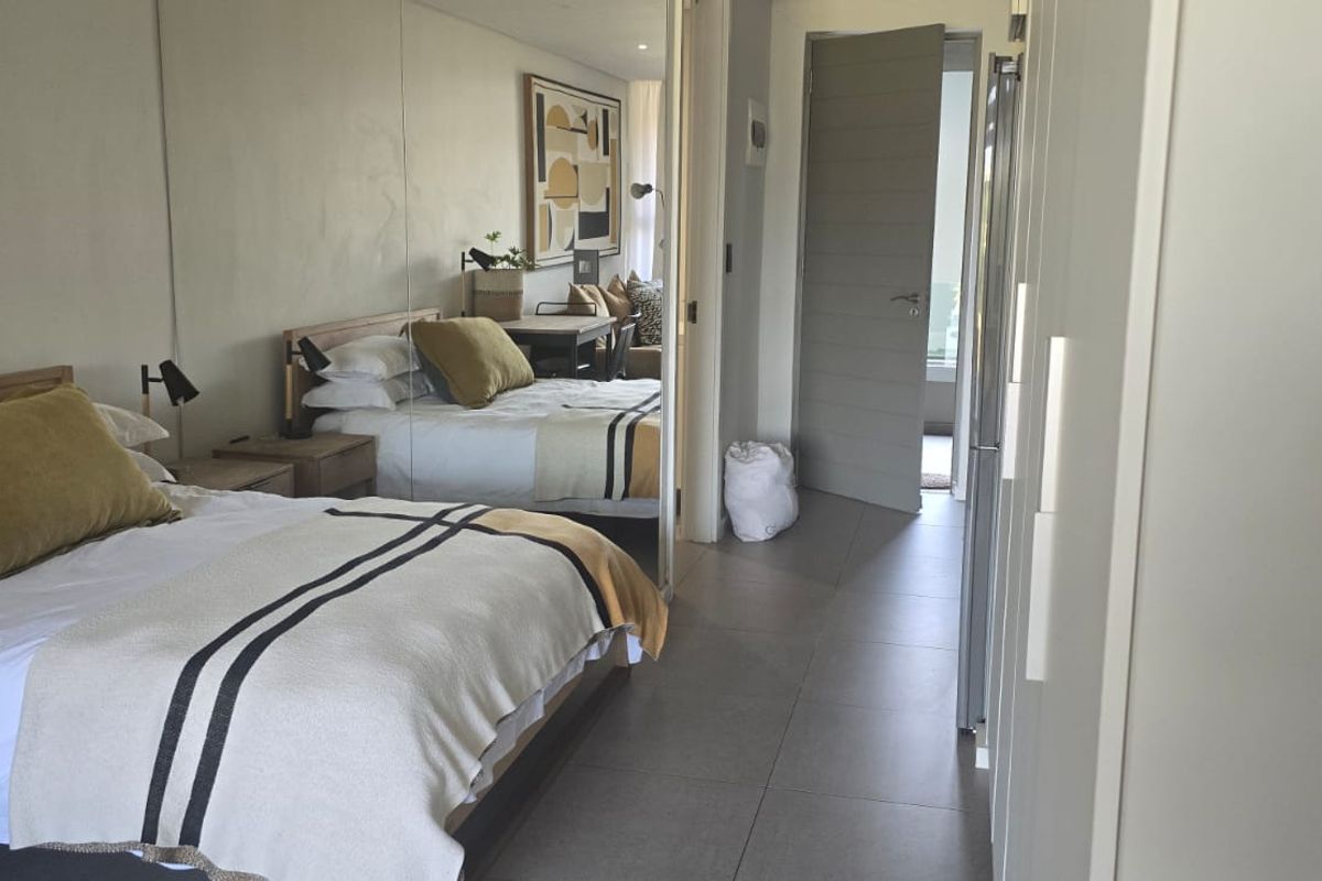 A well-maintained bedroom featuring large mirrored sliding wardrobe doors, modern tiled flooring, and recessed ceiling lighting.
